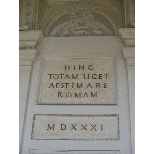 Lähikuva vanhasta rakennuksesta. Rakennuksen seinässä on laatta, jossa on kirjoitusta latinan kielellä.